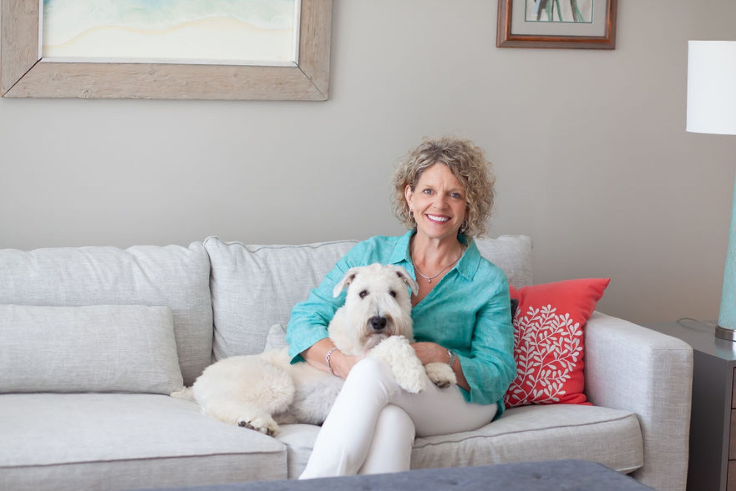Rhonda sitting on a couch with her white dog